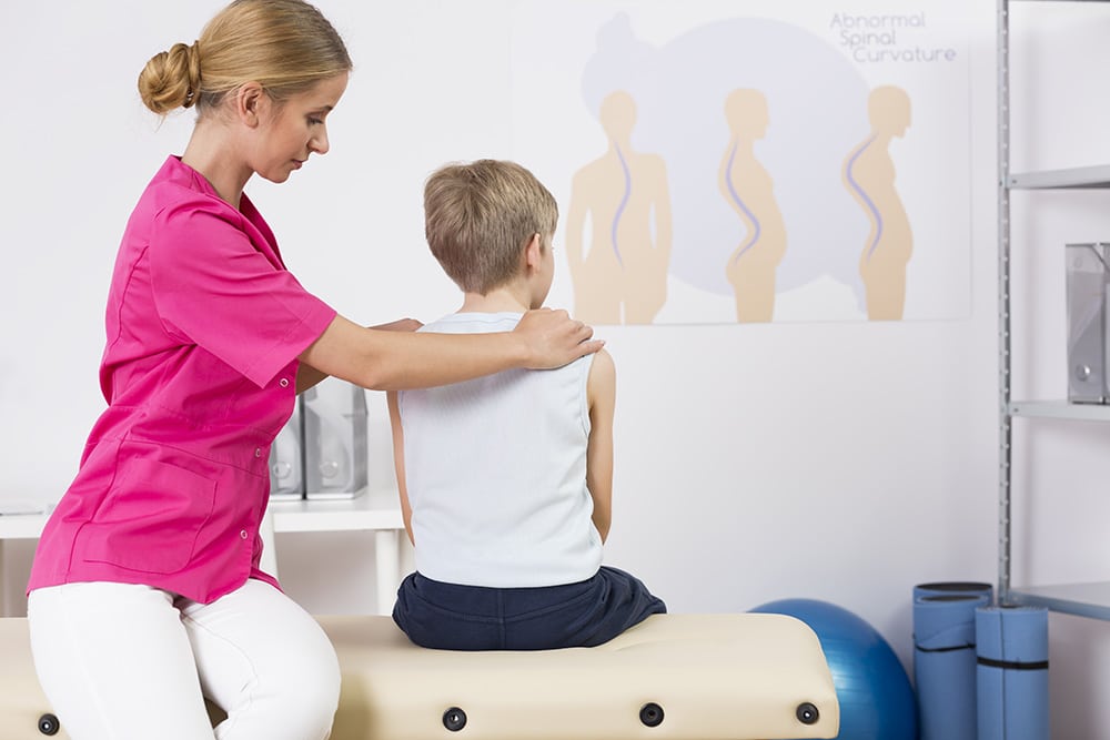 Physiotherapist is correcting the posture of a child